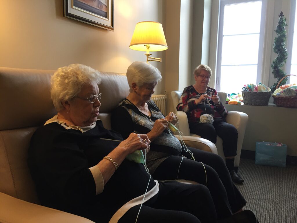 Quatre aînées de la ésidence des berges façonnent des bonnets pour les nouveaux-nés